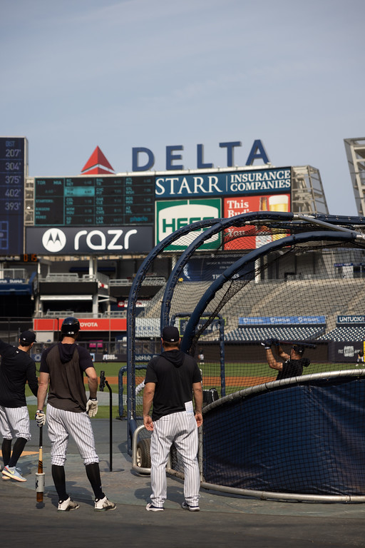 Baseball players near a batting cage at a stadium