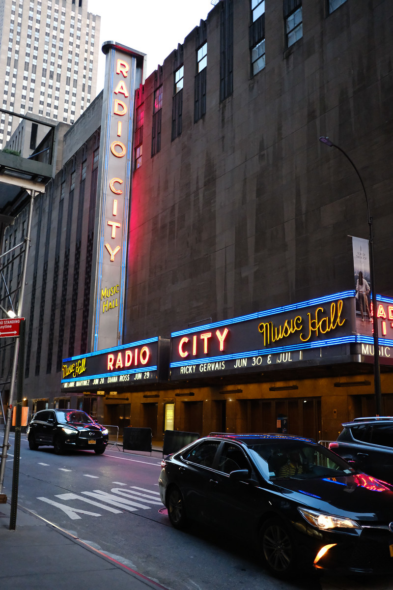 Radio City Music Hall and passing cars on a city street